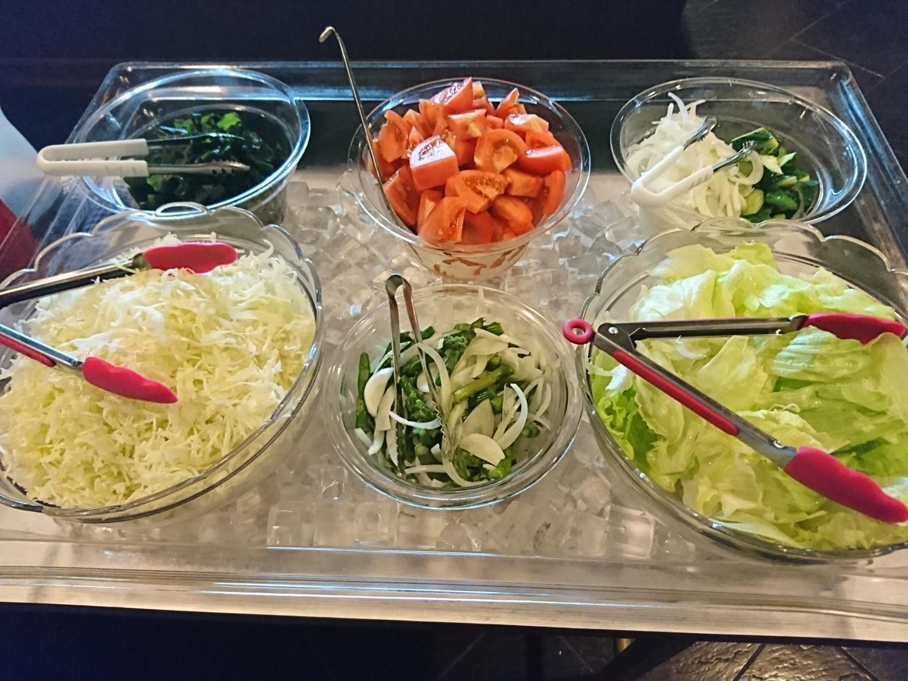 A buffet with various food items including shredded cabbage, sliced carrots, and leafy greens.