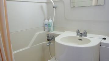 A bathroom with a bathtub, a sink, and a mirror. There are toiletries on the wall.
