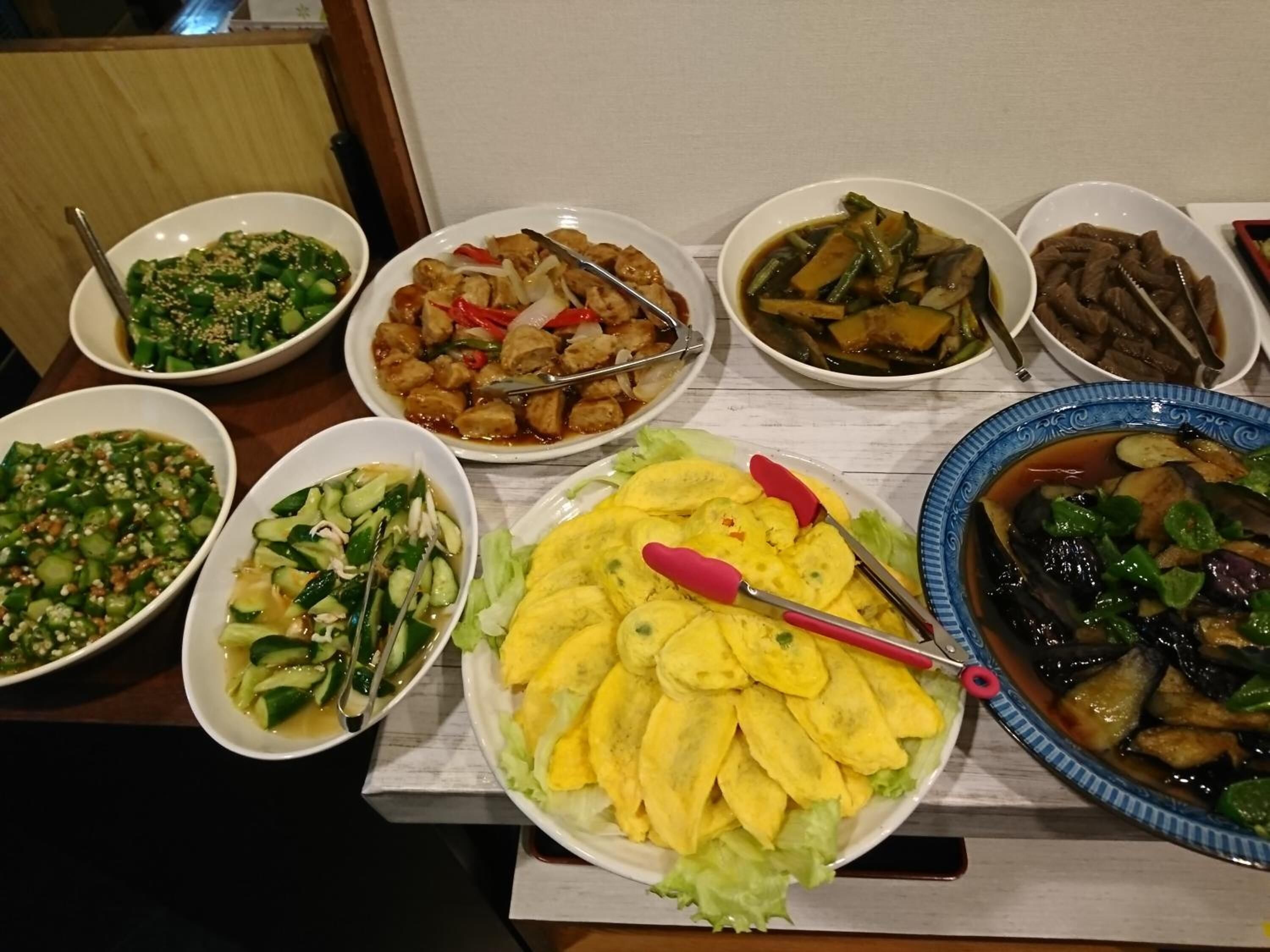Ein Tisch mit verschiedenen Speisen, darunter eine Schüssel geschnittenes Gemüse, eine Portion frittierter Speisen und mehrere Suppenschalen.