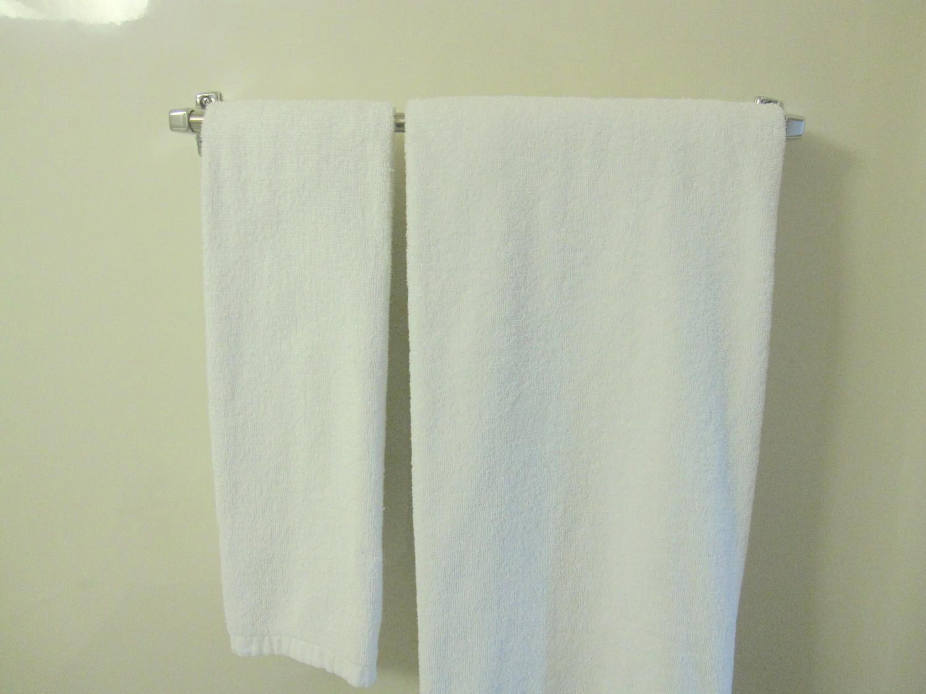 Two white towels hanging on a wall-mounted towel rack.