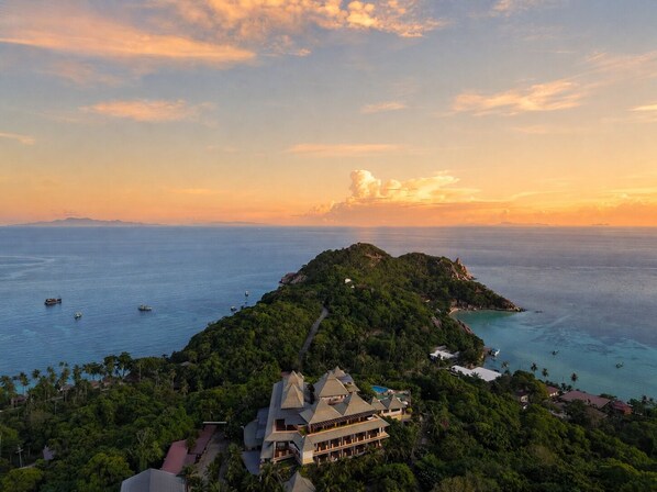 A coastal resort with a prominent building featuring a triangular roof, surrounded by lush greenery and overlooking a clear blue sea. - Ko Tao Paradise Resort (Koh Tao)