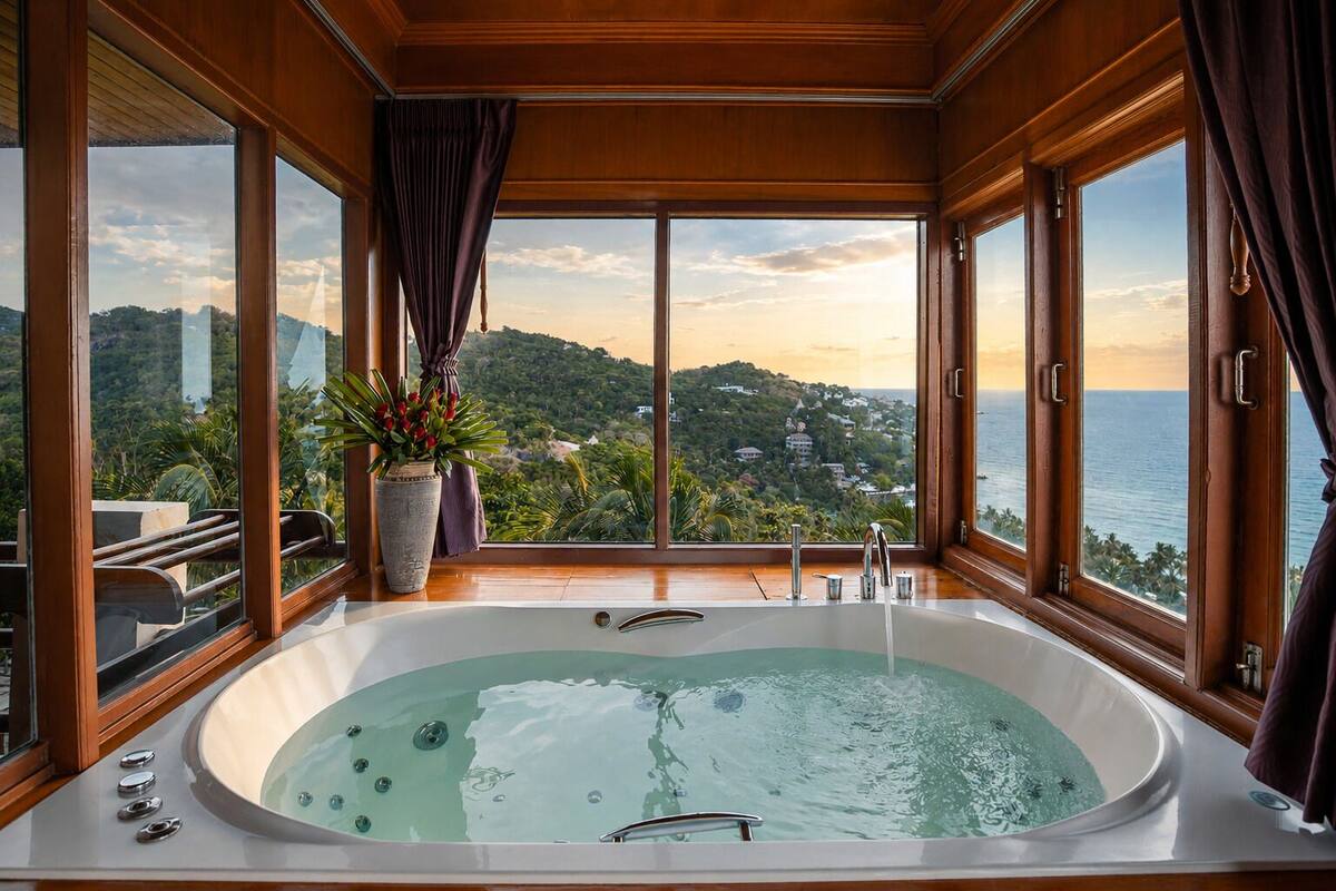 Eine große Badewanne mit Blick auf eine gebirgige Landschaft und das Meer.