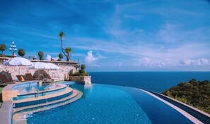 A infinity pool with a stone wall and lounge chairs, overlooking a clear blue sea. - Ko Tao Paradise Resort (Koh Tao)