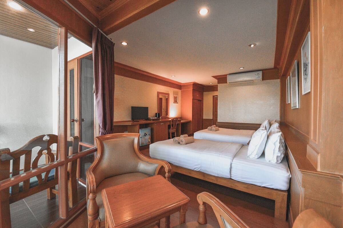 Ein Hotelzimmer mit zwei Betten, einem Schreibtisch, einem Sessel und einem Fernseher.
