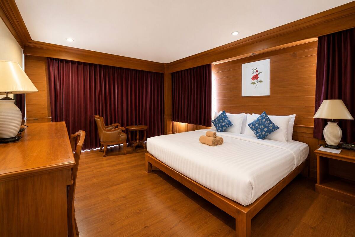 Ein Hotelzimmer mit einem hölzernen Bett, einem Schreibtisch, einem Stuhl und einem kleinen Tisch.