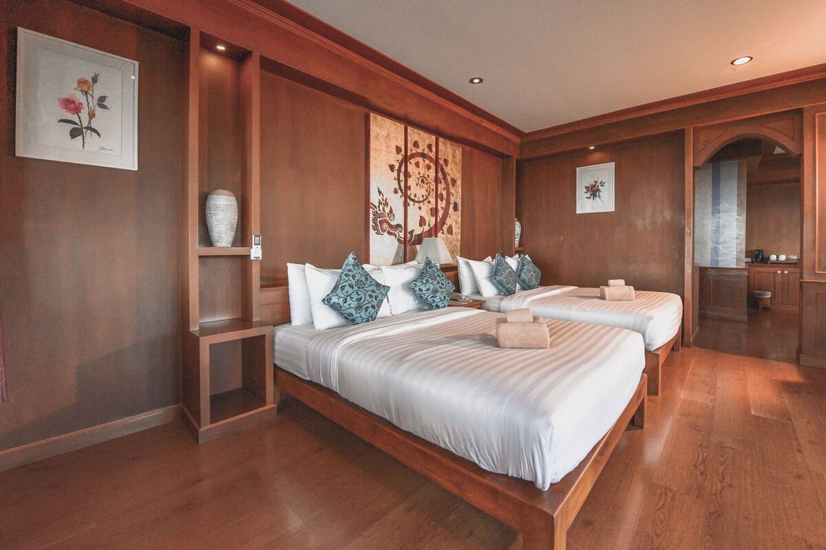 Ein Hotelzimmer mit zwei Betten, Holzboden, einem großen Wandbild und einer kleinen Küchenzeile.
