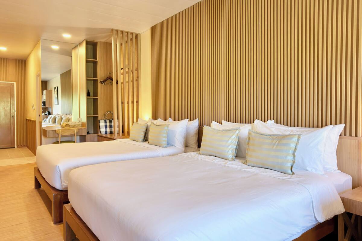 Ein Hotelzimmer mit zwei Betten, Holzwandverkleidung, einem Schreibtisch mit Stuhl und einem Kleiderschrank.
