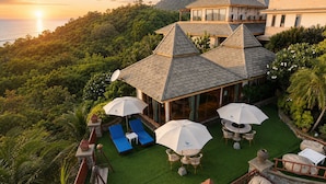 A resort with a rooftop terrace, outdoor seating, and a view of the ocean.