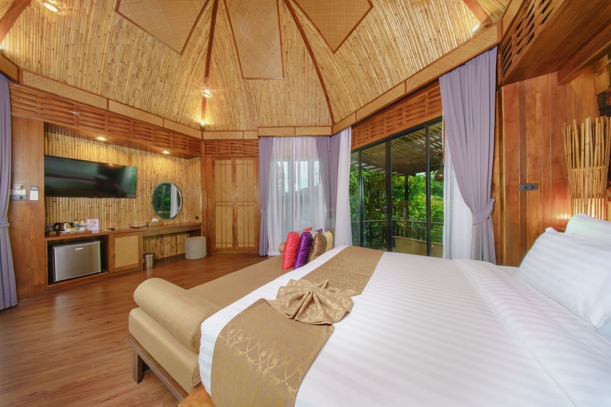 A room with a bed, a sofa, a TV, and a small kitchenette.
