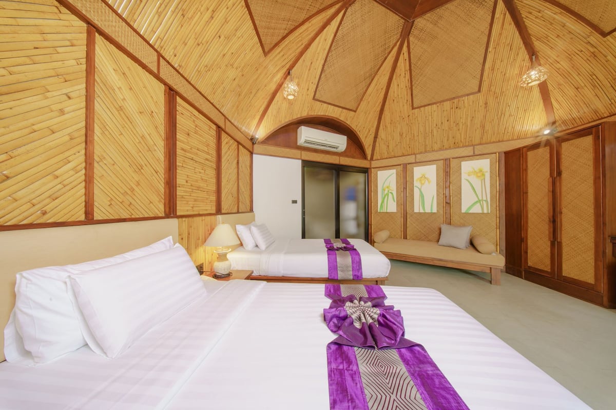 A room with two beds, a sofa, and a sliding door.