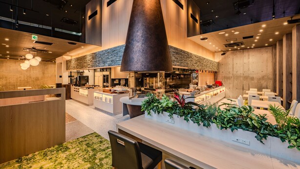 Een modern interieur met een centraal gelegen keuken, zithoeken en een receptiebalie.