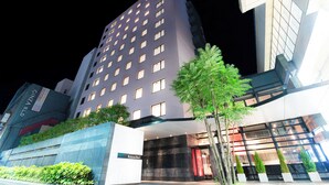 Een modern hotel met een opvallende ingang, meerdere verdiepingen en een goed verlichte gevel.