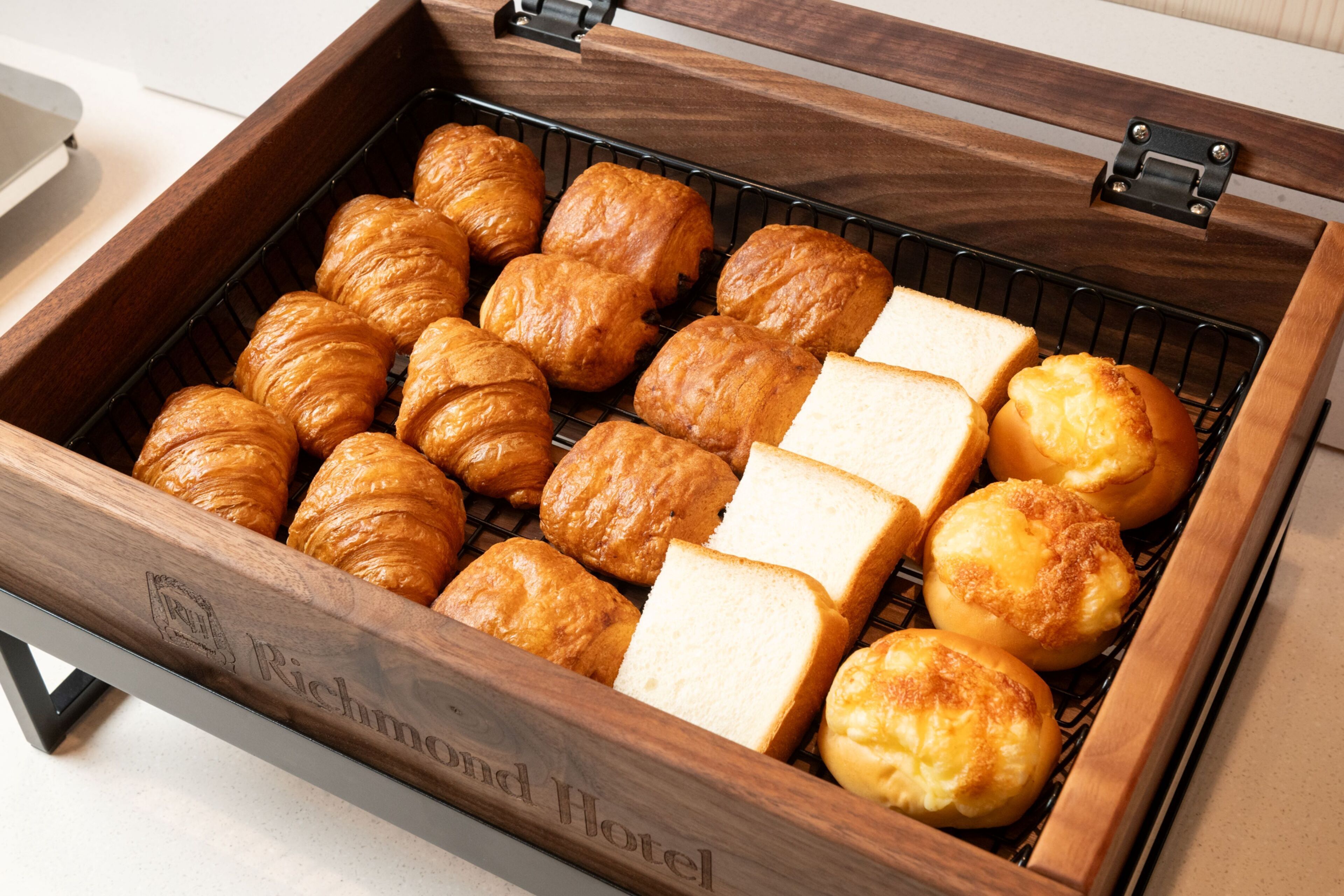 Ein Holztablett mit verschiedenen Backwaren, darunter Croissants und Brot.