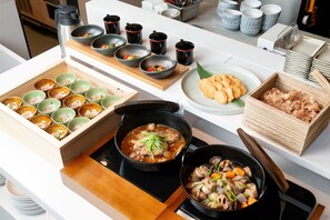 Een keukentrap met verschillende gerechten, waaronder kommen met eten, een stoofpot en een bord koekjes.