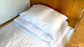 A neatly made bed with white bedding and a wooden headboard. - Backpacker's Home (Seogwipo)