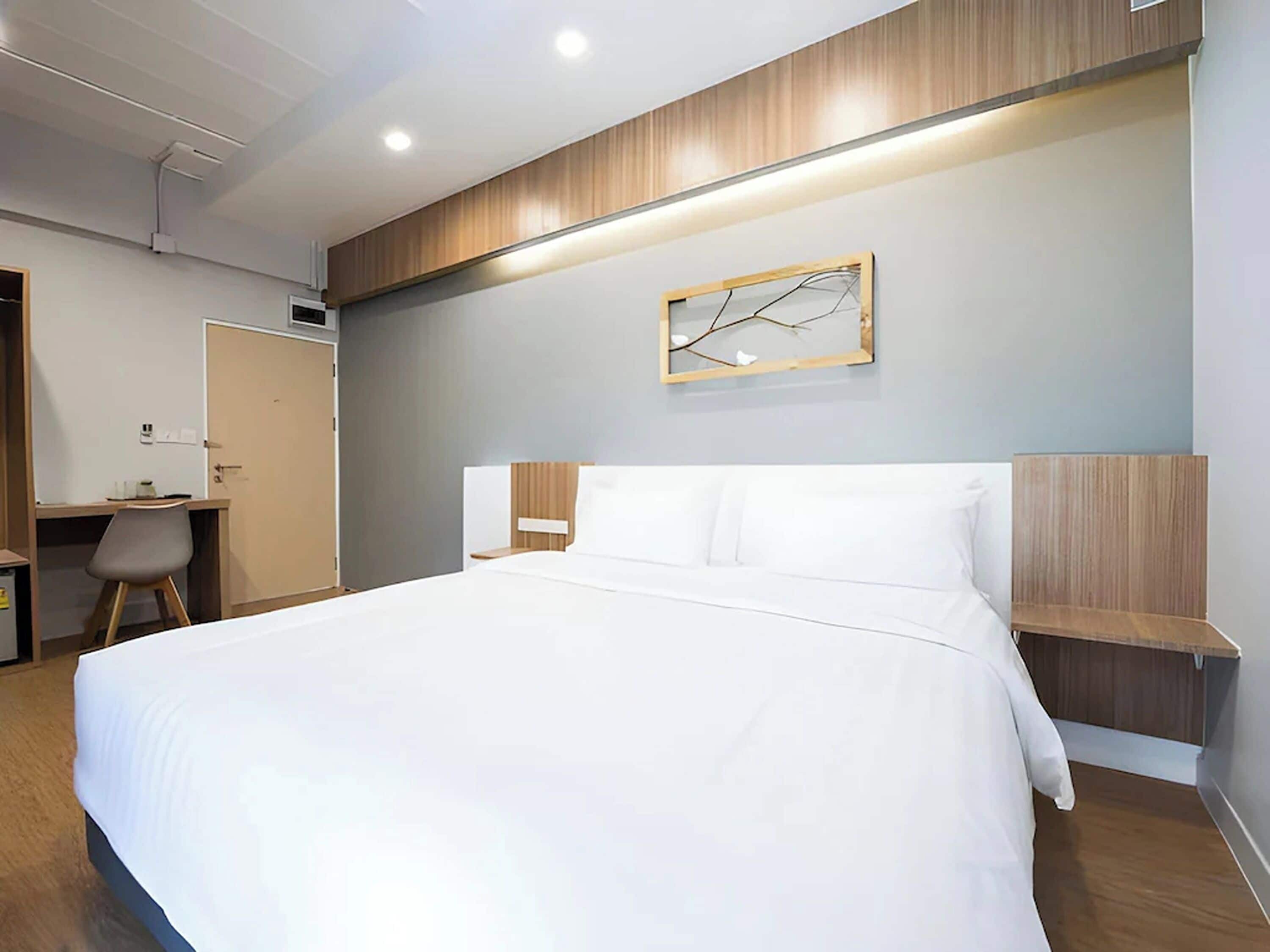 A modern hotel room with a large bed, a desk, and a chair.