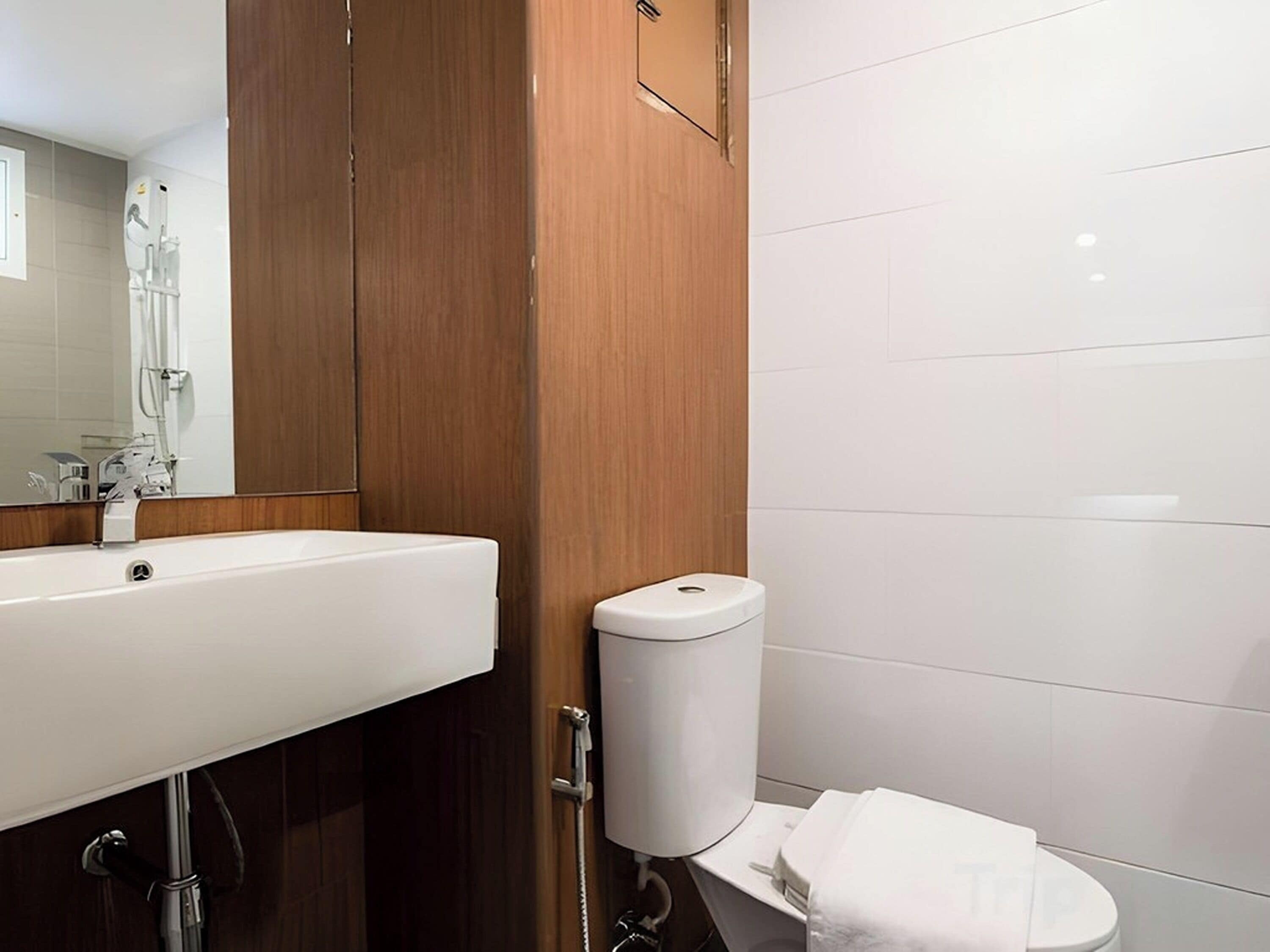 Une salle de bain avec un lavabo blanc, des toilettes et un meuble en bois.
