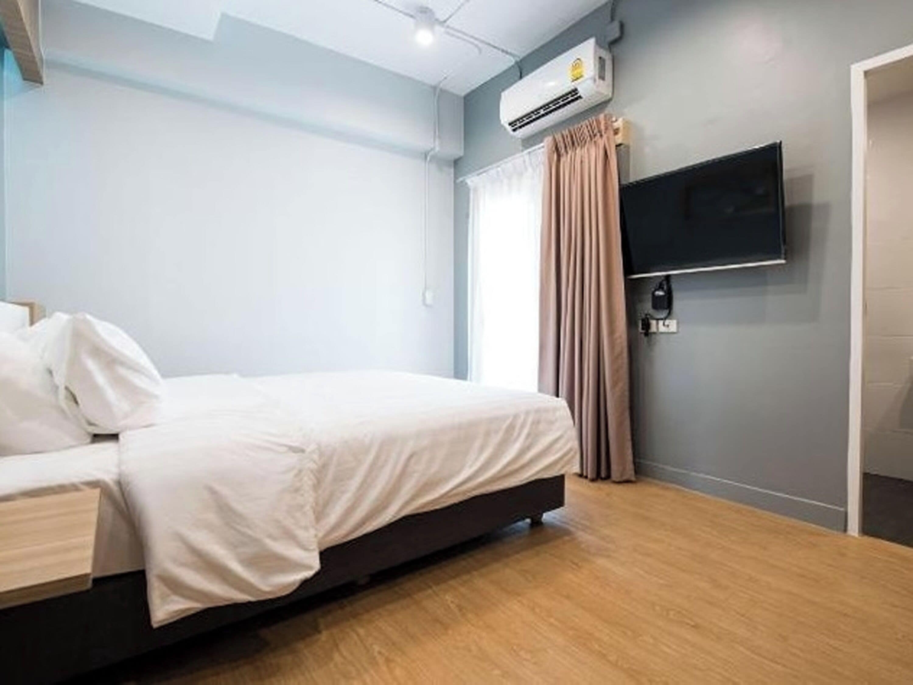 Ein Hotelzimmer mit einem Bett, einem flachbildfernseher an der Wand und einer Klimaanlage.