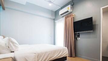 Ein Hotelzimmer mit einem Bett, einem flachbildfernseher an der Wand und einer Klimaanlage.
