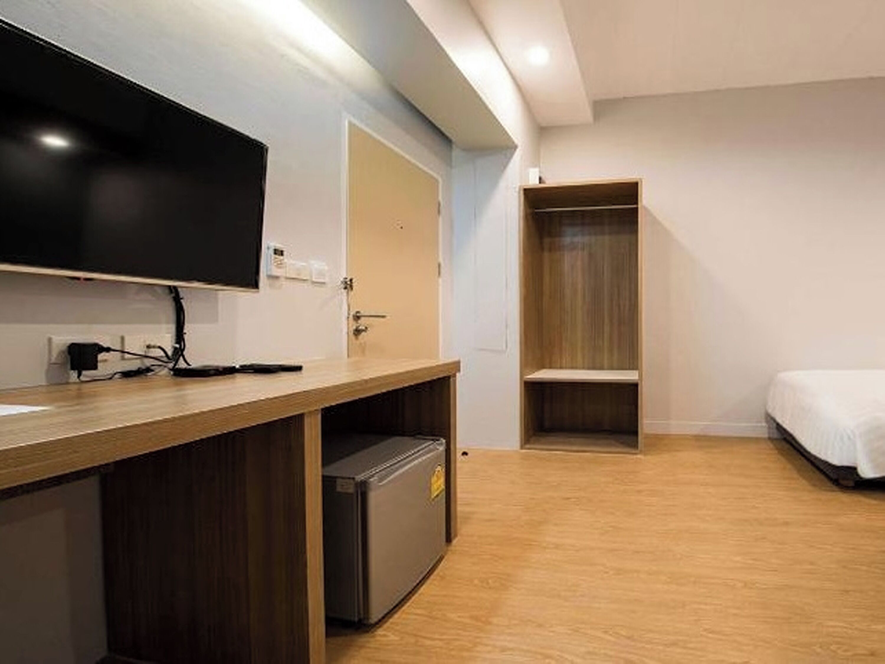A hotel room with a wooden desk, a television, a wardrobe, and a bed.