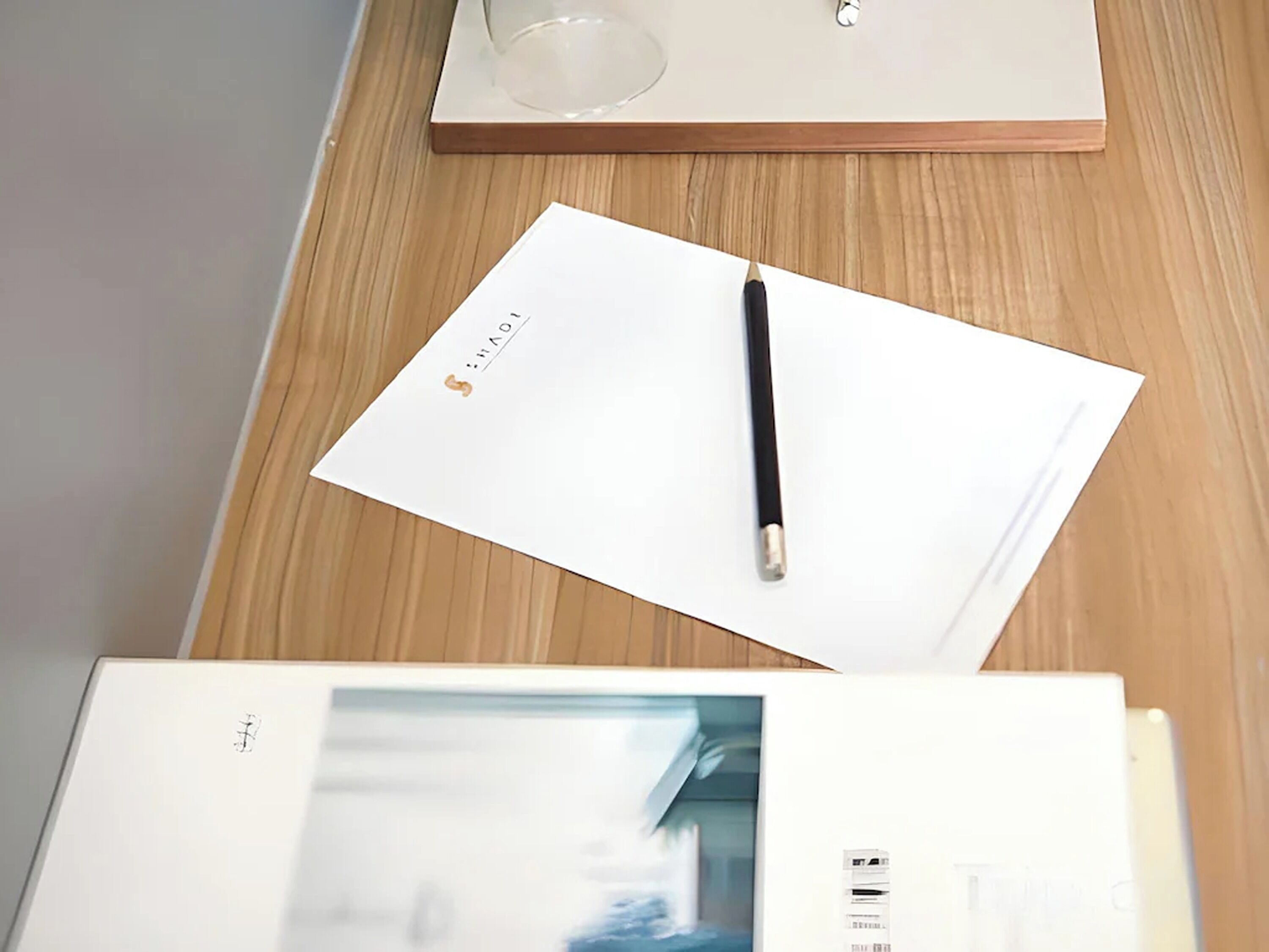 A wooden table with a white notepad, a black pen, and a book.