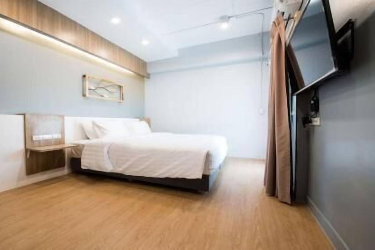 A modern bedroom with a bed, bedside table, and a mounted TV.