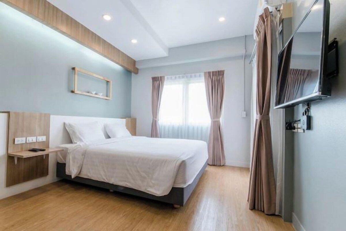 Une chambre d’hôtel moderne équipée d’un lit, d’une table de chevet, d’une télévision et de rideaux.