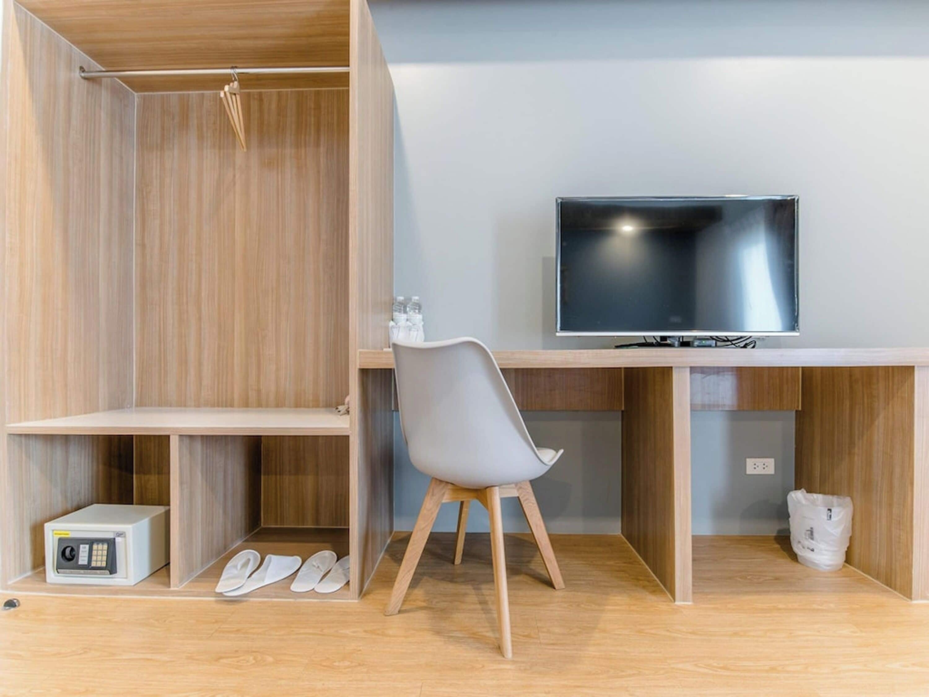 Una habitación moderna con escritorio de madera, televisor, silla y microondas.