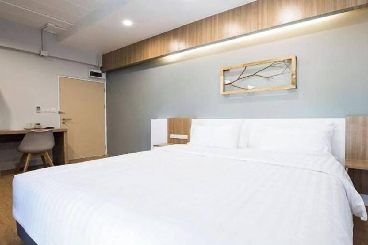 A hotel room with a bed, a desk, and a chair.