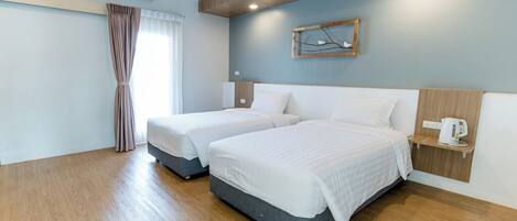 Habitación de hotel con dos camas, techo de madera, unidad de aire acondicionado y estante con hervidor.