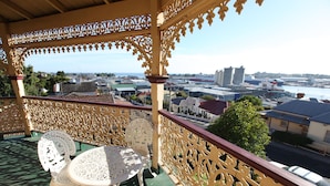 A balcony with ornate railings, a table, and two chairs. - The Grand On Macfie (Devonport)