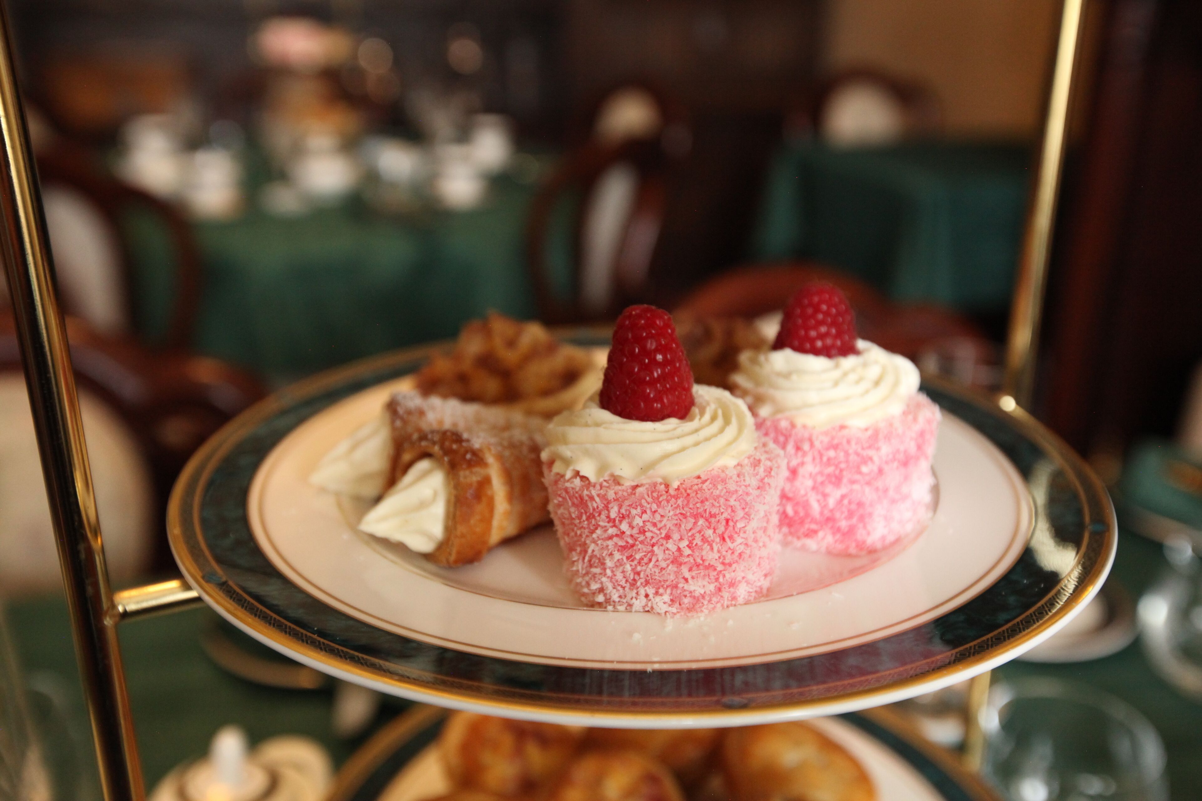Un expositor escalonado para postres con pasteles y un postre cubierto de fresas.