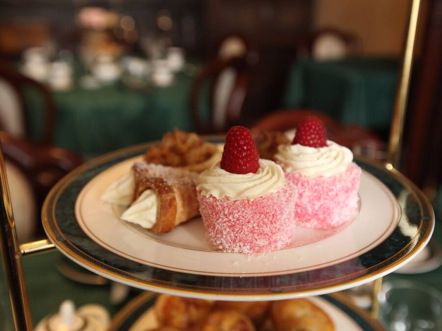 Un expositor escalonado para postres con pasteles y un postre cubierto de fresas.