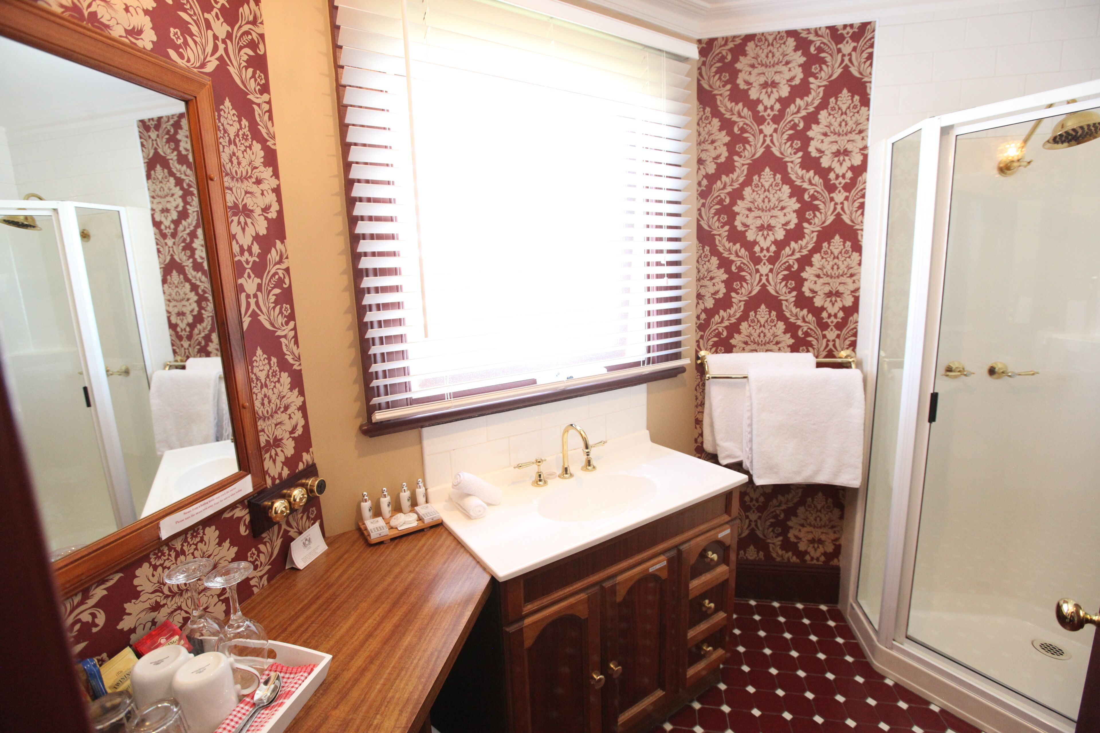 A bathroom with a vanity, sink, mirror, and shower.