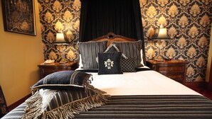 A neatly made bed with striped bedding and decorative pillows, a dark curtain, and patterned wallpaper. - The Grand On Macfie (Devonport)