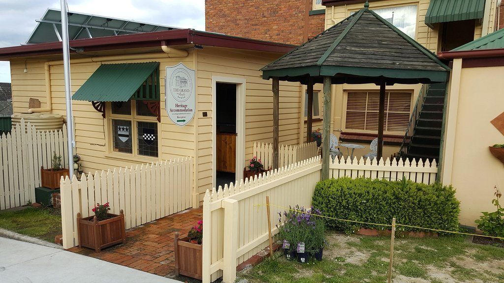A heritage accommodation with a wooden exterior, a white picket fence, and a small garden area.