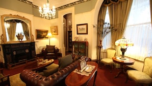 A traditional living room with a fireplace, leather sofa, and classic decor. - The Grand On Macfie (Devonport)