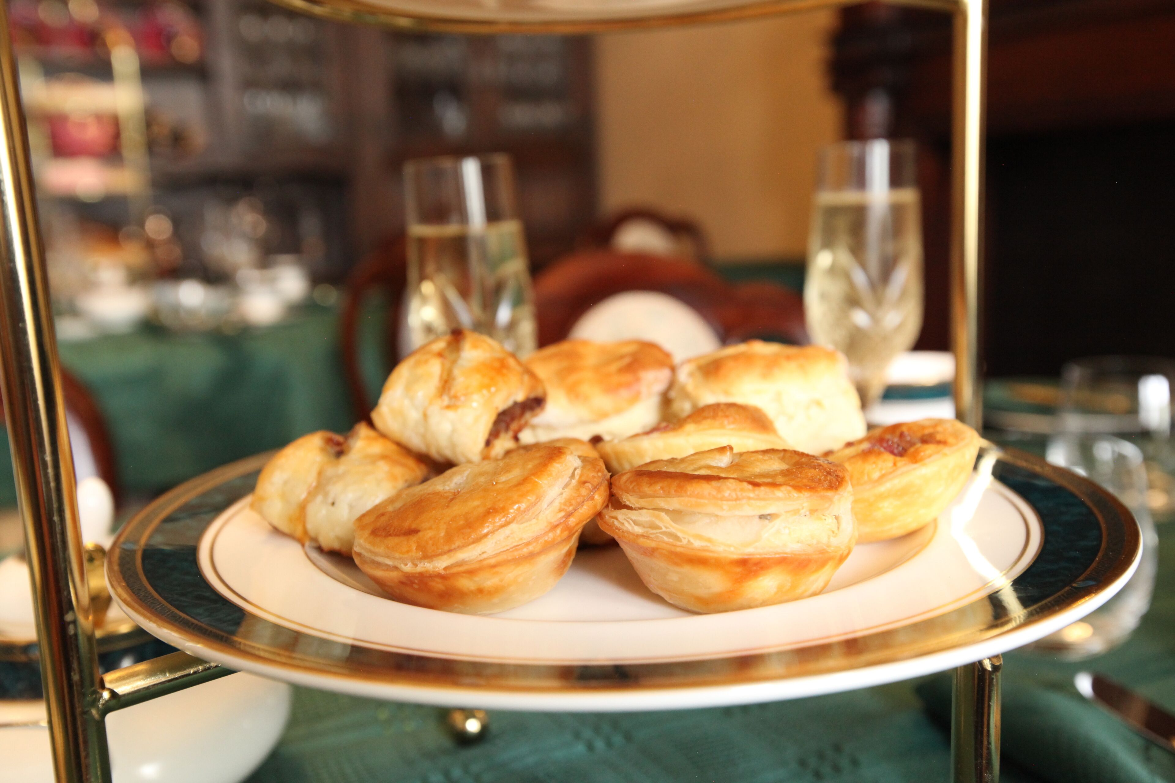 Une assiette de pâtisseries est posée sur une table, avec des verres d’eau et une bouteille en arrière-plan.
