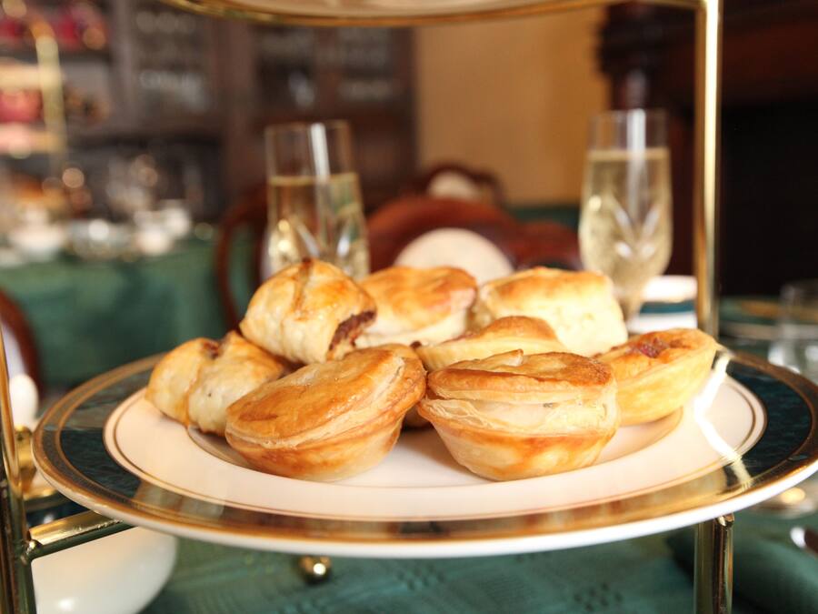 Une assiette de pâtisseries est posée sur une table, avec des verres d’eau et une bouteille en arrière-plan.