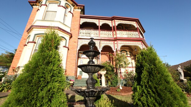 A historic building with a prominent corner turret, a decorative balcony, and a central fountain. - The Grand On Macfie (Devonport)