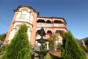 Ein historisches Gebäude mit einem markanten Eckturm, einem Zierbalkon und einem zentralen Brunnen.
