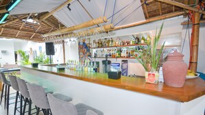 A bar area with a long counter, multiple stools, and a variety of bottles and glasses. - Boracay Backpackers (Boracay Island)