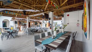 A restaurant with a thatched roof, wooden tables, and chairs. - Boracay Backpackers (Boracay Island)