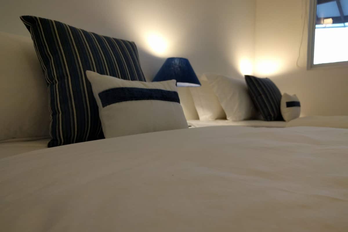 A neatly made bed with white bedding and striped pillows.