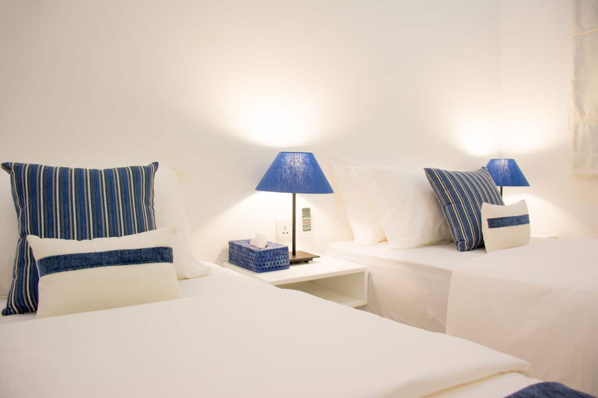 A hotel room with two beds, white bedding, and blue striped pillows.