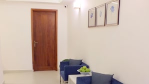 A modern living room with a wooden door, a blue sofa set, a white coffee table, and a potted plant. - The Residence (Colombo)
