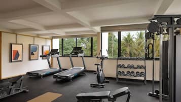 Un gimnasio con cintas de correr, elípticas, prensa de banca y mancuernas.