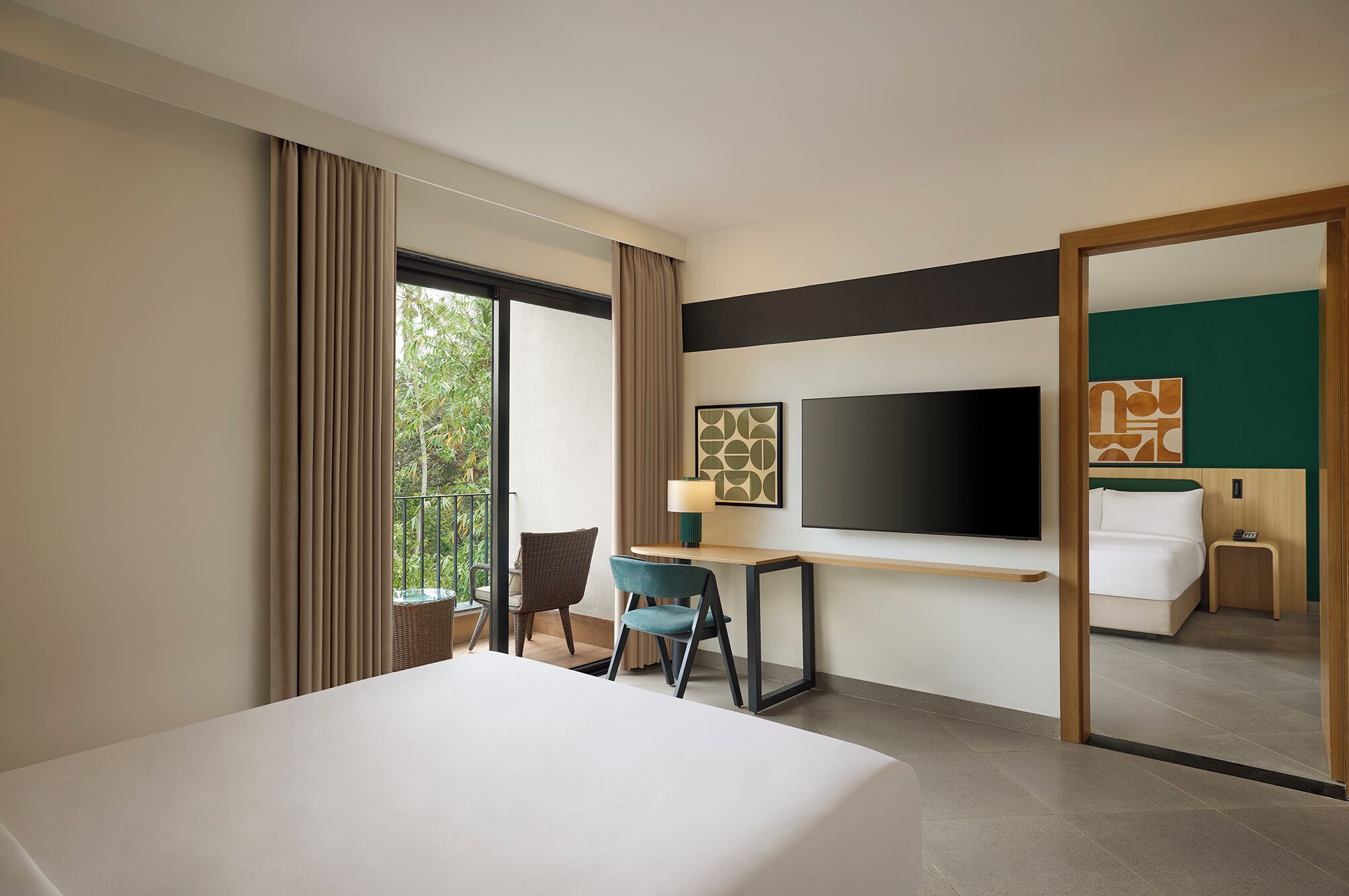 A hotel room with a bed, a desk, a chair, a TV, and a large mirror.