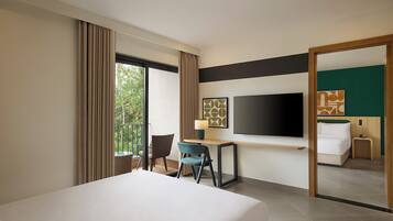 A hotel room with a bed, a desk, a chair, a TV, and a large mirror.