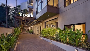A modern hotel entrance with a 'spark' sign, a brick pathway, and lush greenery. - Spark by Hilton Goa Calangute (Calangute)